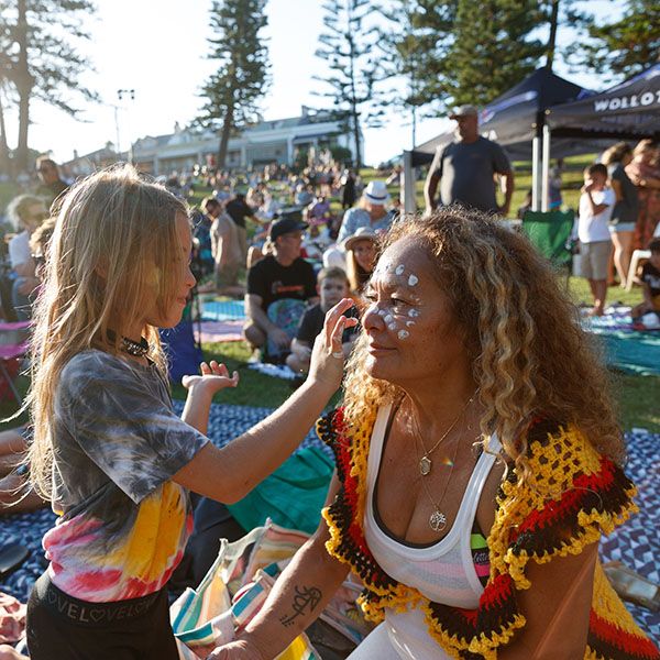 An Aboriginal girl lovingly paints her grandmother's face atthe Ngarrama event